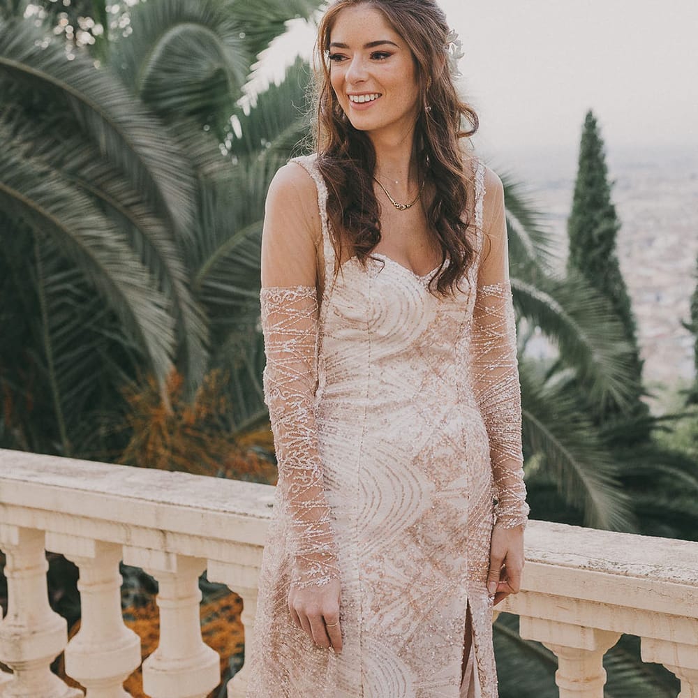 Bride with long hair in a bespoke gold sparkly wedding dress with illusion long sleeves