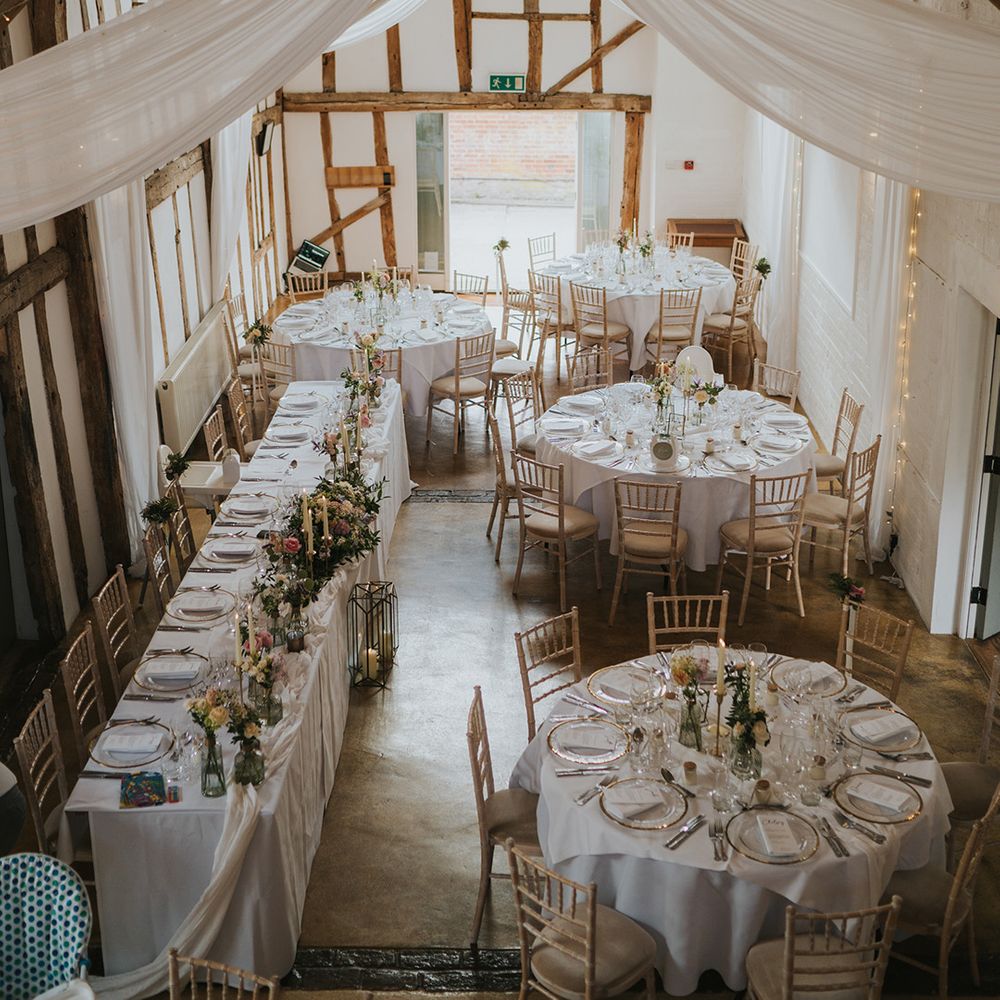 Dove Barn Weddings reception room with white drapery and fairy lights with a classic white tablescape and pastel flowers 