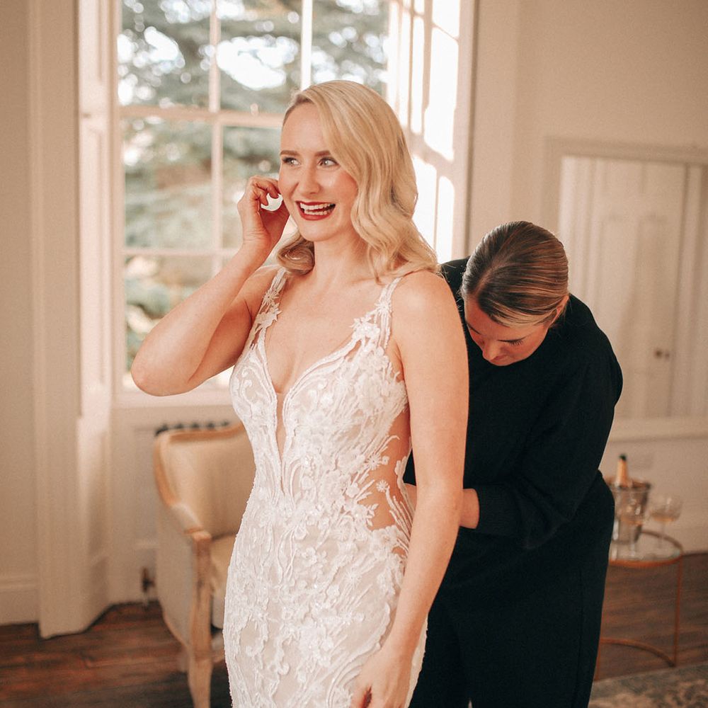 Bride steps into her fitted lace wedding dress at classic winter wedding 