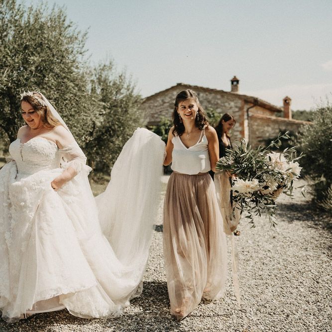 Bridesmaid helping Bride with her dress and olive bouquet