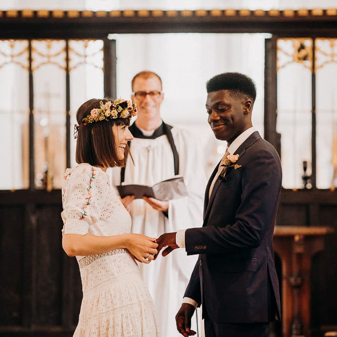 Bride in a laser cut and embroidery wedding dress putting on her grooms wedding ring 