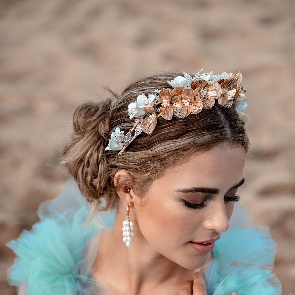 Bride with smokey eyeshadow, and natural lipstick wearing a gold flower headband and dangly earrings 