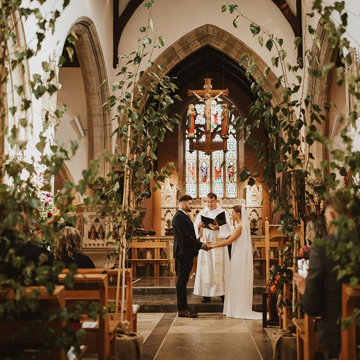 Trees lining the church wedding ceremony aisle with bride and groom exchanging vows at the altar 