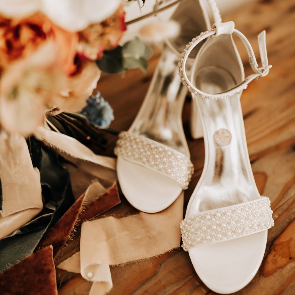 White bridal heels with pearl detailing next to pastel bridal bouquet