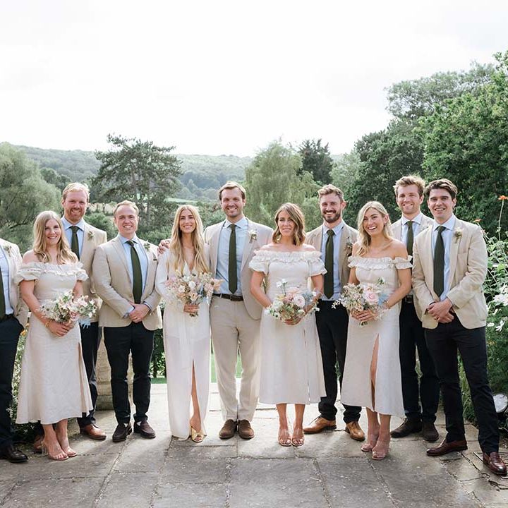 Bride and groom pose with their bridesmaids and groomsman with English countryside for a backdrop