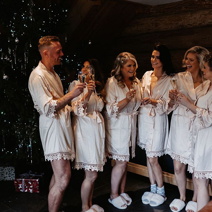 Bridal party get ready for the wedding day and have a toast in front of a Christmas tree for winter wedding 