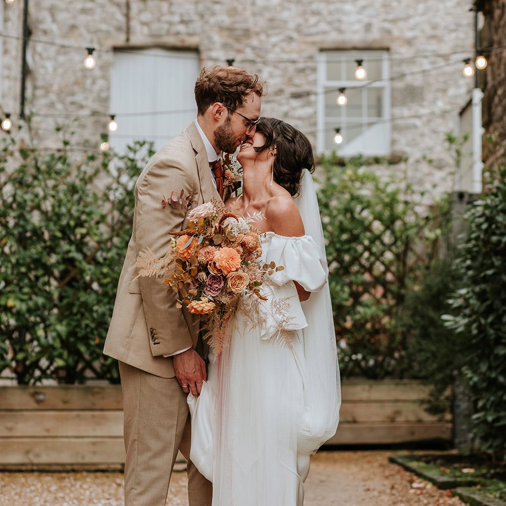 Bride and groom lean in for a kiss after their wedding ceremony at industrial wedding venue