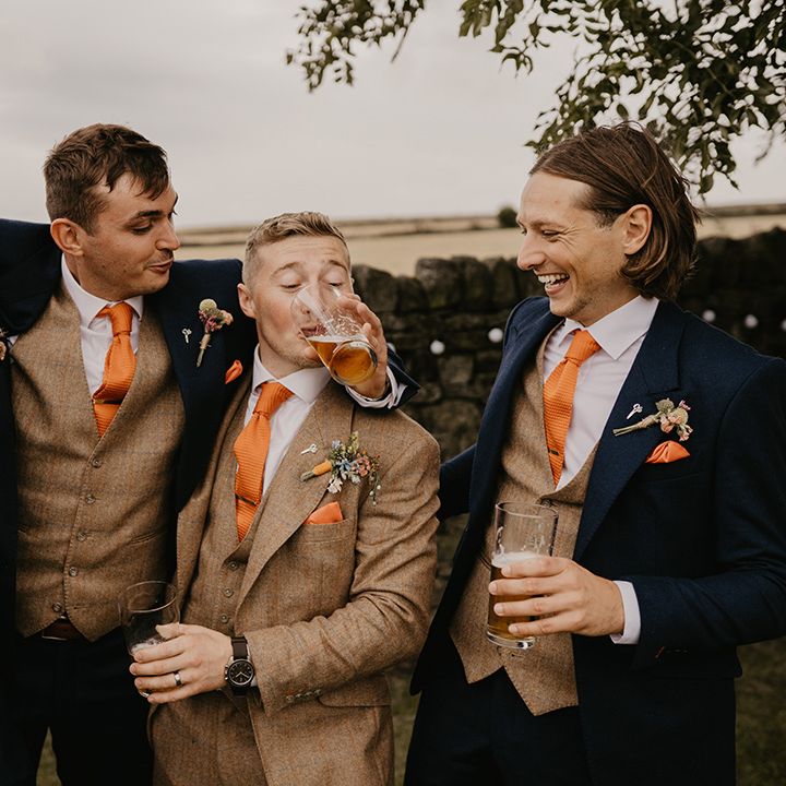 Groomsmen and the groom all stand together with their pints as the groom drink from his friends glass