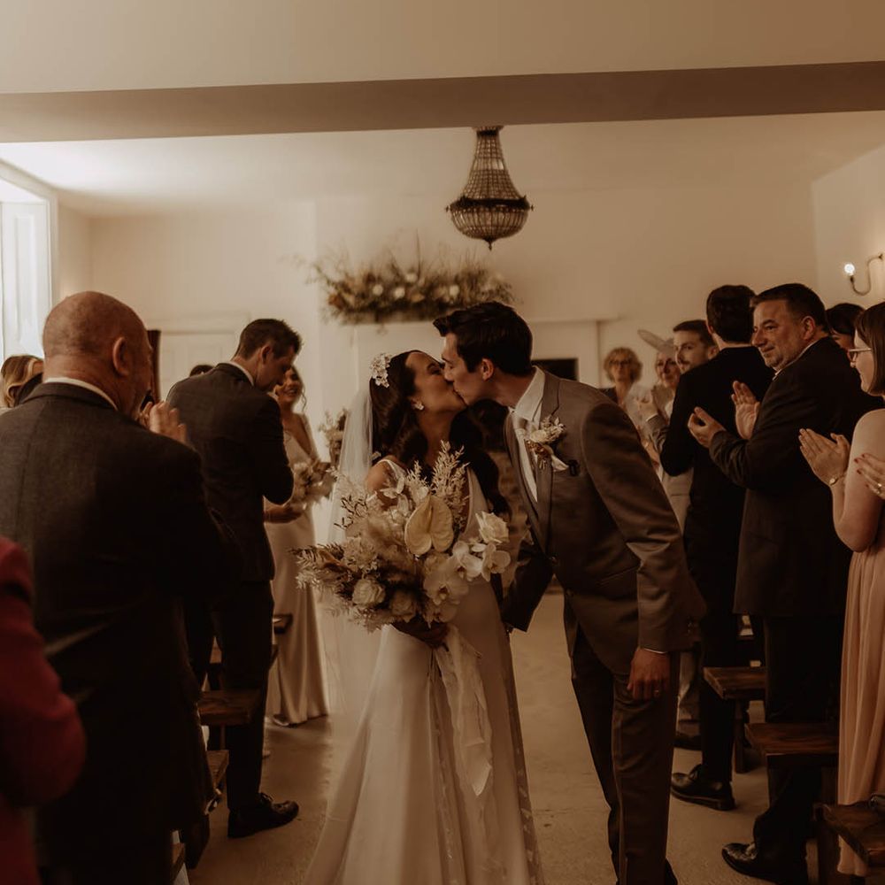 Bride and groom share a kiss as they walk back down the aisle as a married couple at their boho luxe wedding 