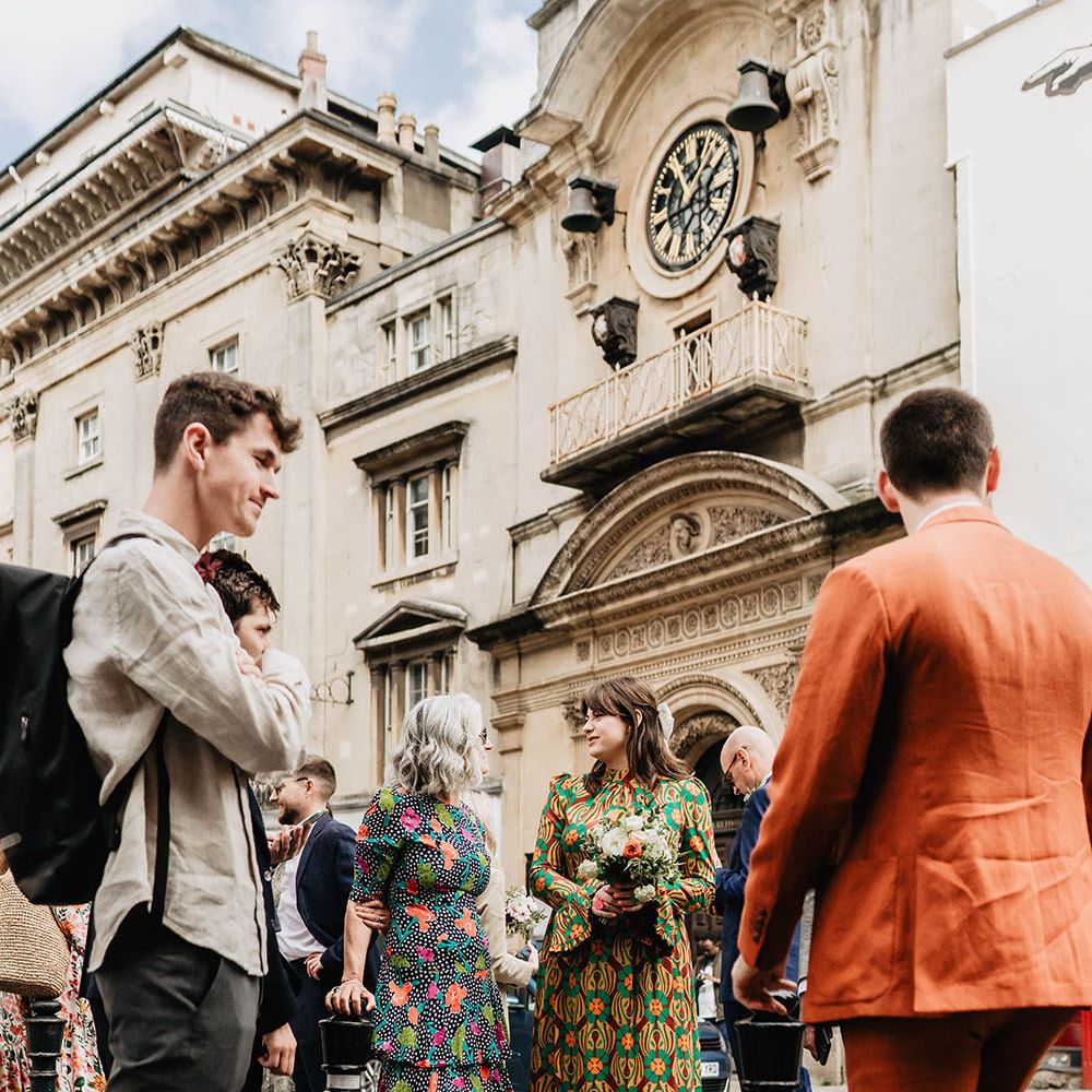 Wedding guests in brightly coloured clothing gather outside Bristol Register Office 