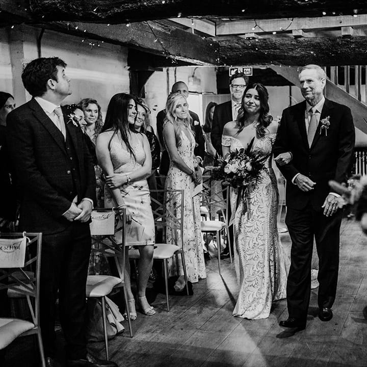 Father of the bride walks the bride in a boho lace wedding dress down the aisle 
