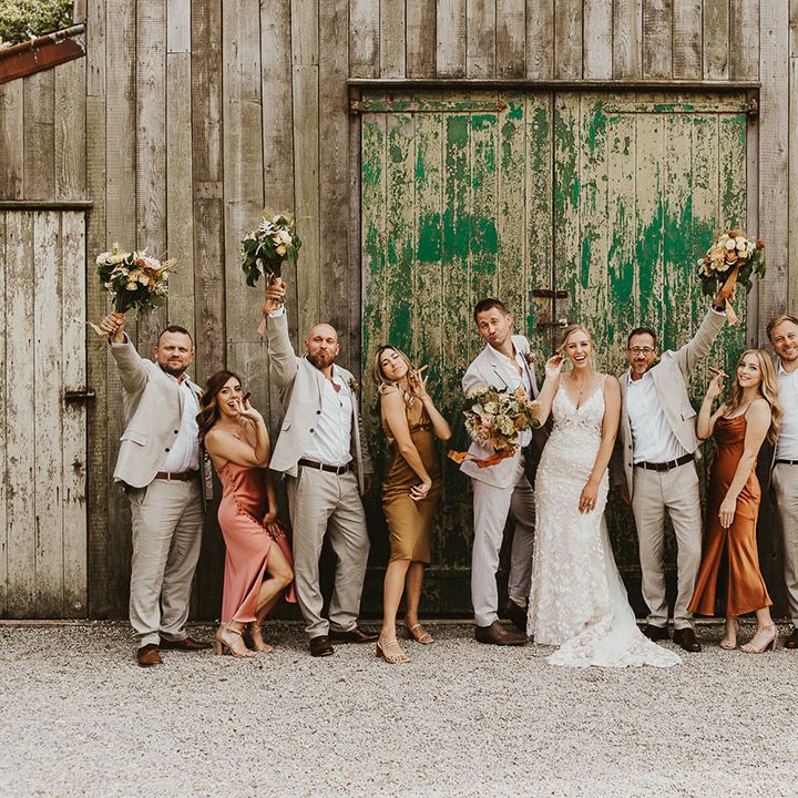 Groomsmen lift up the bridesmaid's bouquets for cute wedding party photo 