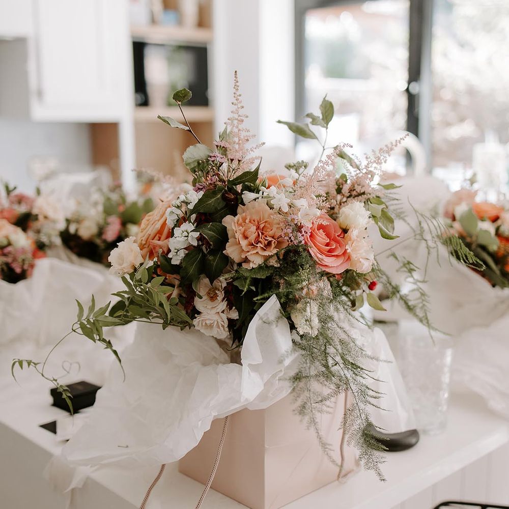 Bridal bouquet with pastel floral and green foliage surrounded by white tissue paper 