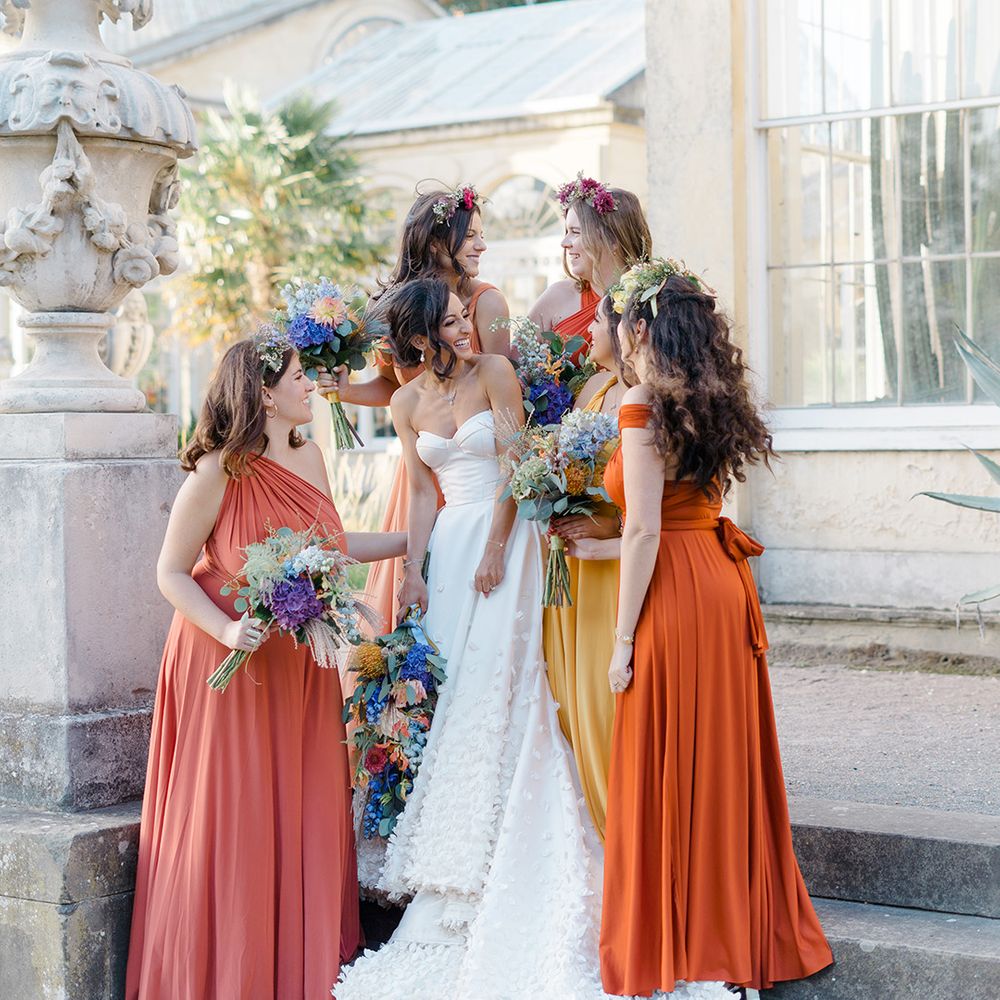 Bride in bespoke Emma Beaumont design wedding dress stands with her bridesmaids in ombre styled yellow and orange bridesmaid dresses