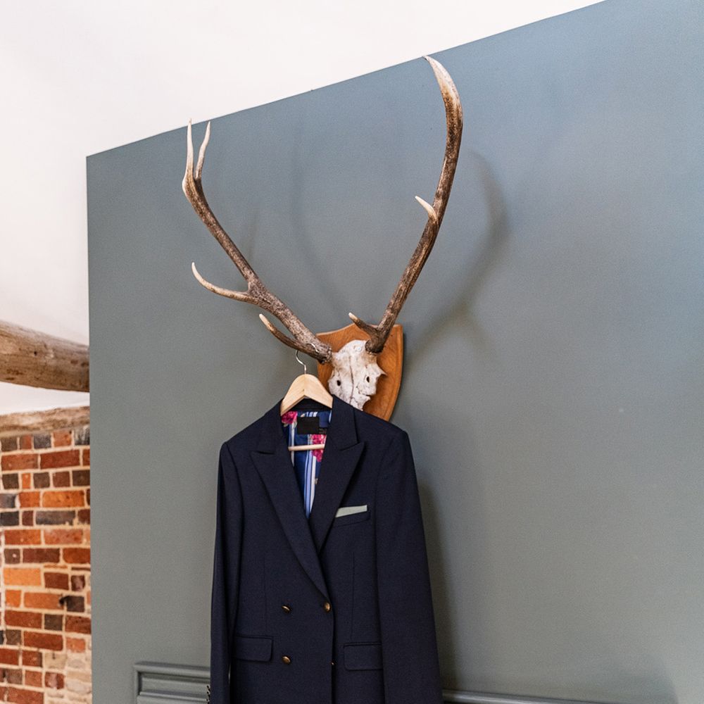 Grooms blue double breasted blazer hangs upon rustic skull decor on the morning of his wedding day