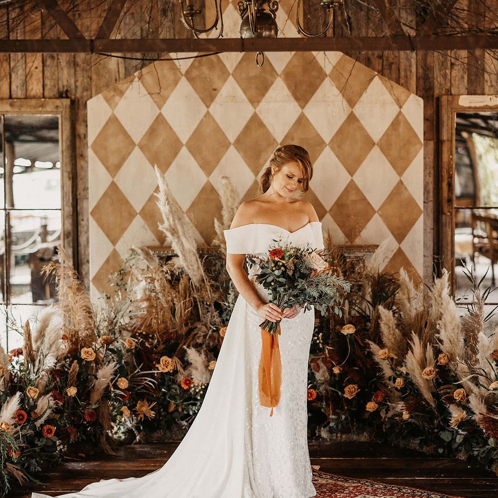 Bride stands in front of pampas grass dried floral installation with Autumnal styling at The Dreys