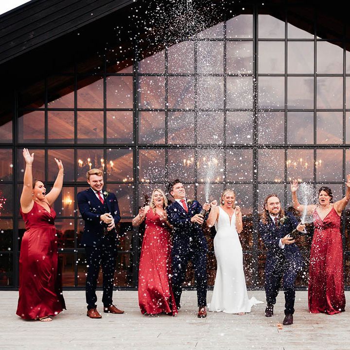 The wedding party pop champagne to celebrate the wedding of Jade & James 