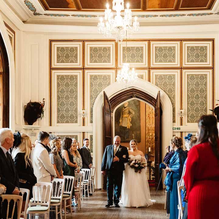 Bride in off shoulder tulle wedding dress walking down the aisle at Drumtochty Castle wedding venue Scotland with father of the bride 
