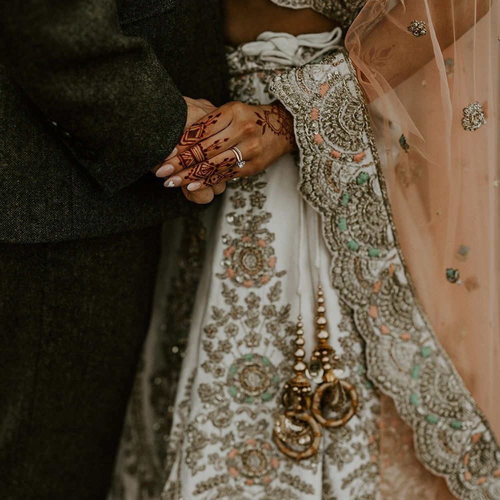 Bride in sparkly lehenga holding hands with the groom 