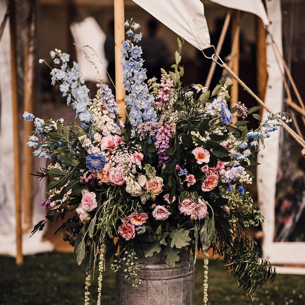 Light pink and baby blue wedding flower arrangements in milk churn for rustic decor