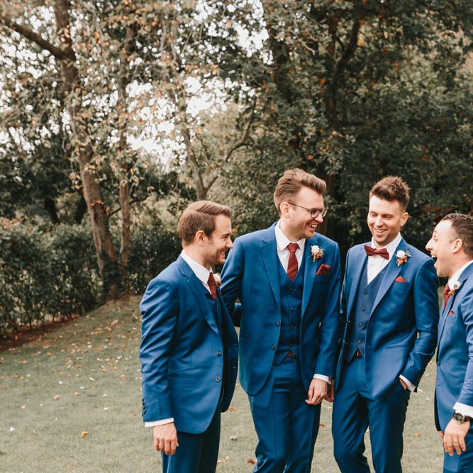 Groomsmen in navy suits laughing together 