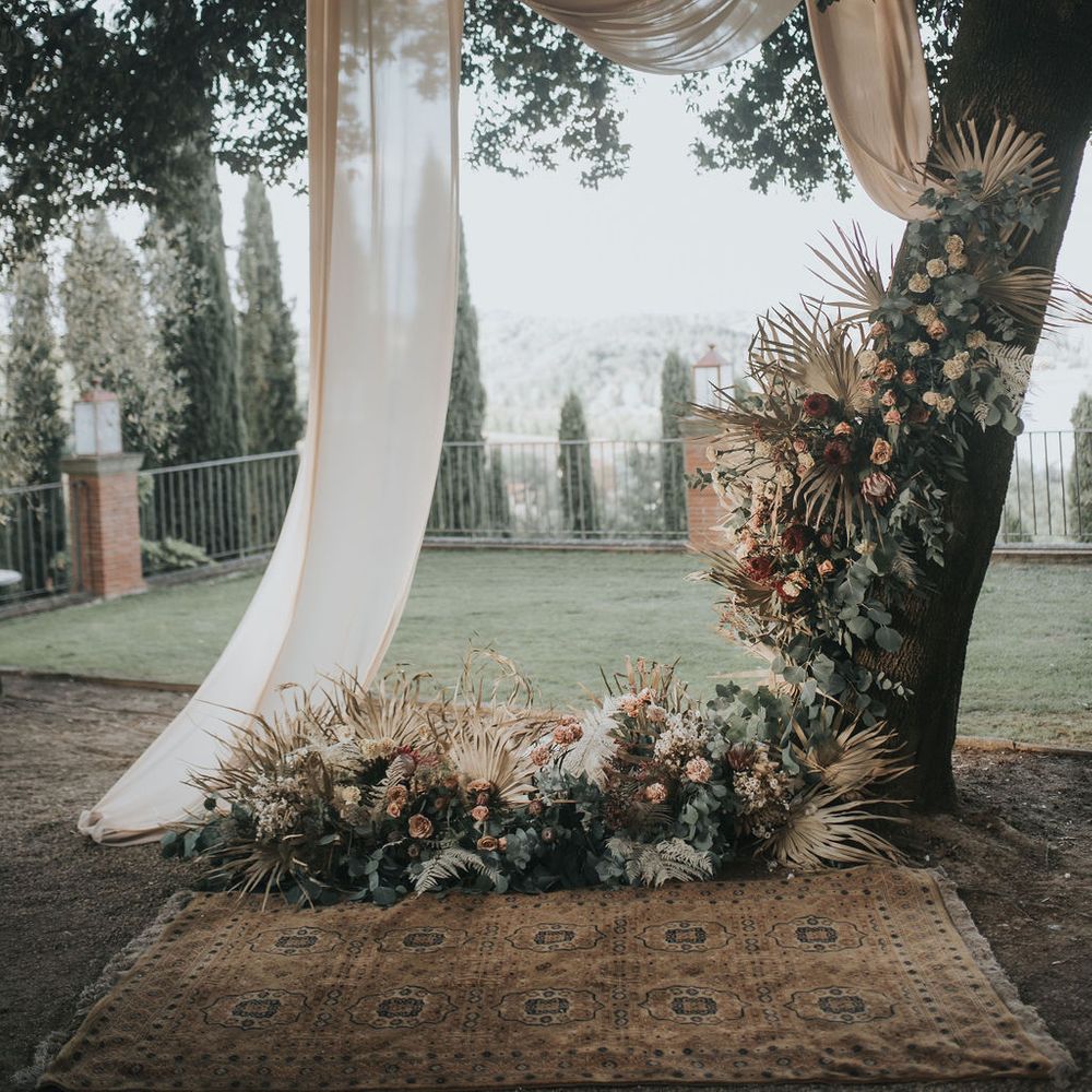 Ceremony altar decorated with drapes and flowers at Tuscany wedding 