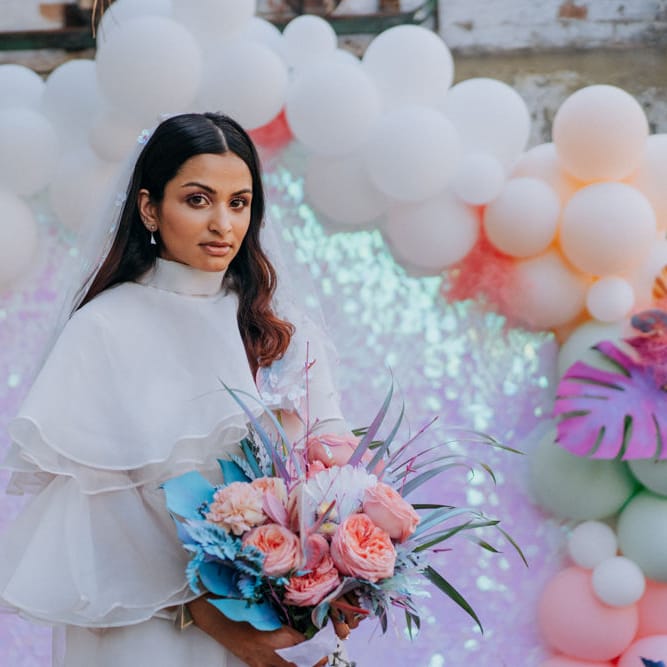 Bride in short wedding dress and boots holding her holographic pastel bouquet 