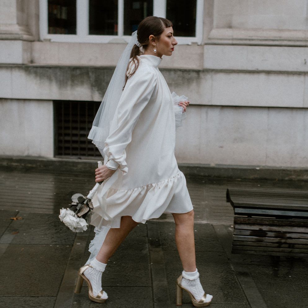 Stylish bride in a silk Felicity wedding dress with Celeste veil, gold Gucci shoes and socks 