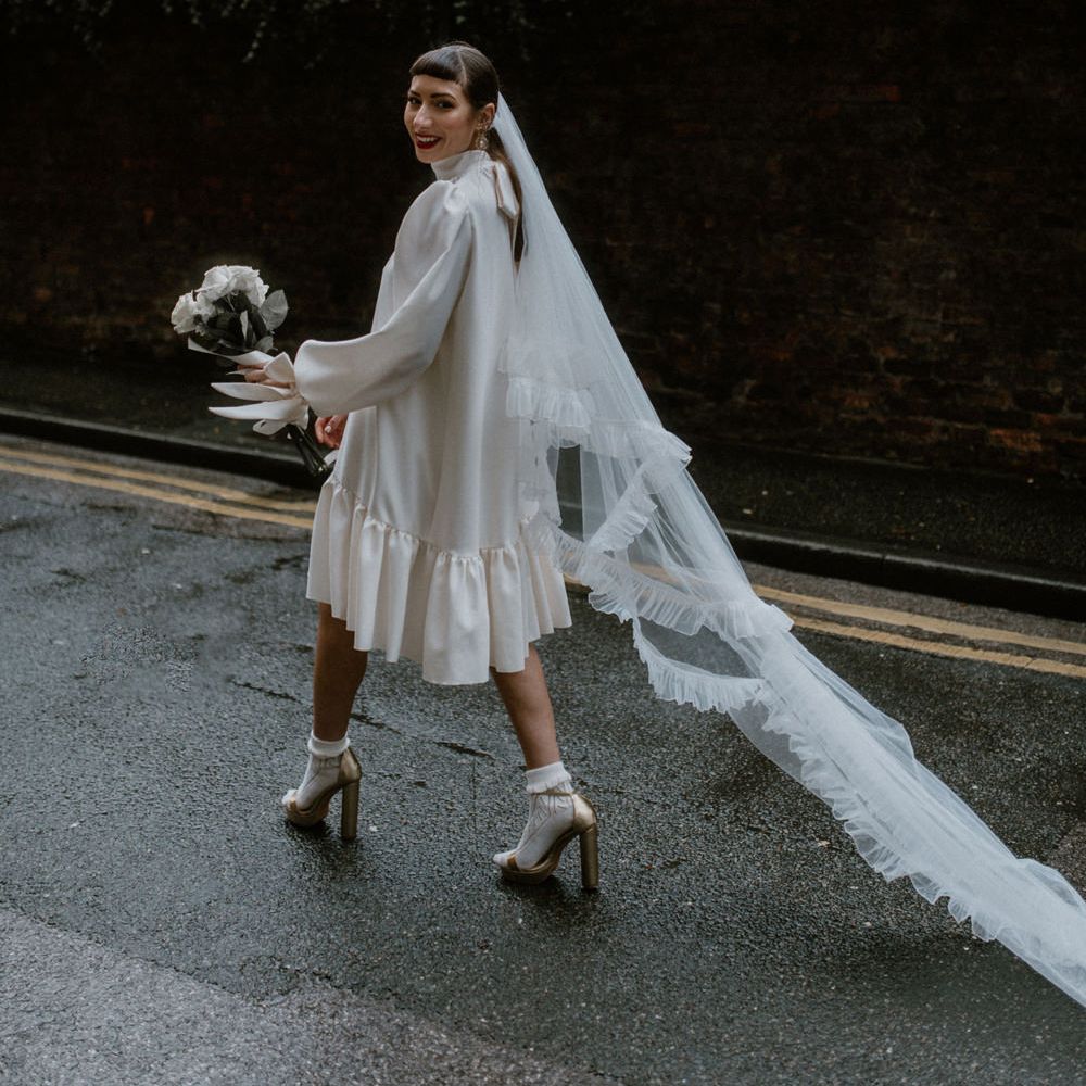 Bride in a silk wedding dress with gather hem and tulle veil with ruffled edges 