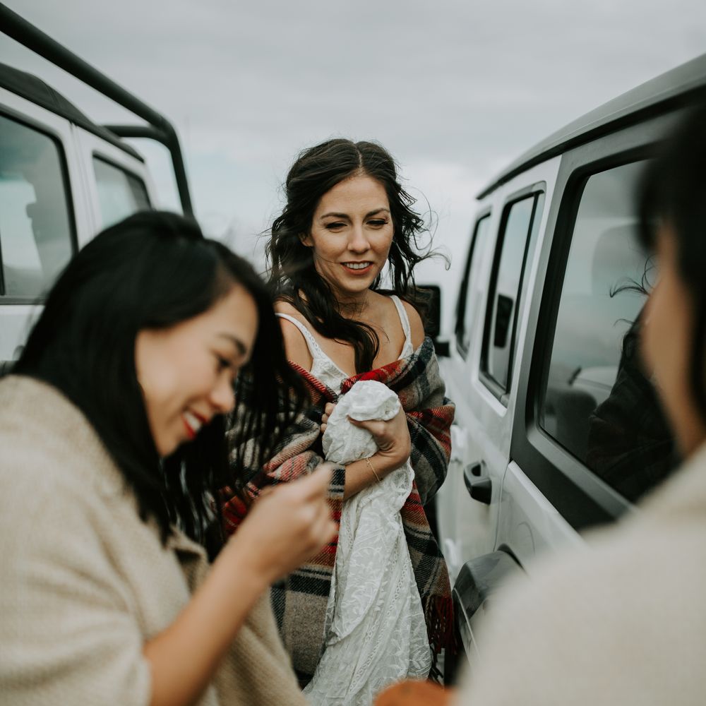 Bride stands between wedding Jeep cars whilst getting ready