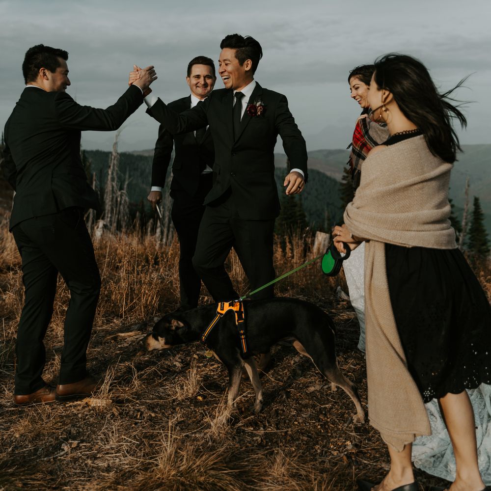 Groom celebrates with wedding party on mountain tops