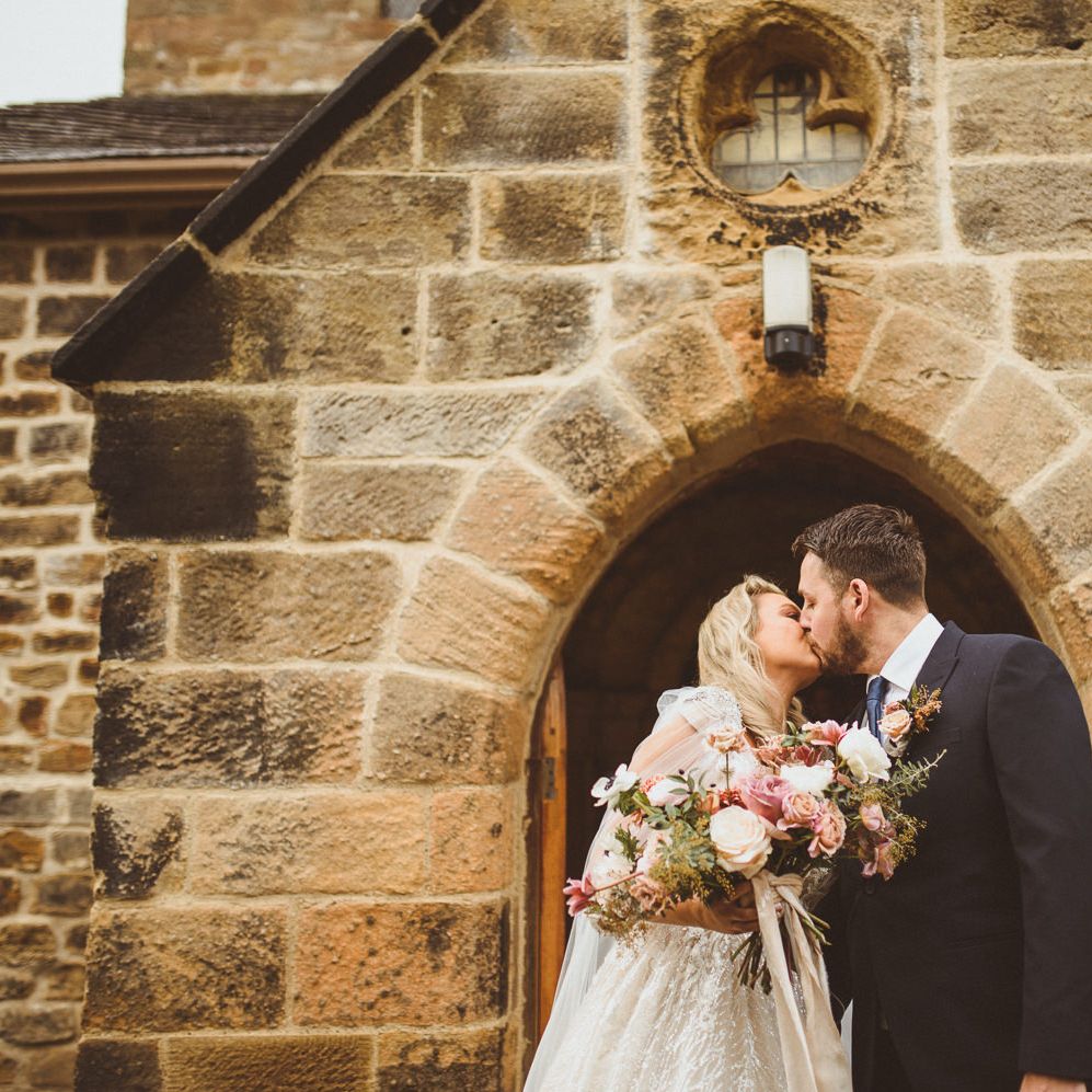 Bride and groom kissing outside their church wedding