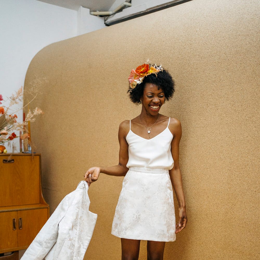 Bride wearing wedding separates of a white mini skirt with matching blazer, and a spaghetti strap bridal top