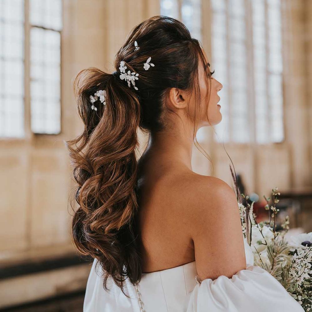 Bride with a full high ponytail decorated with flower hair clips 
