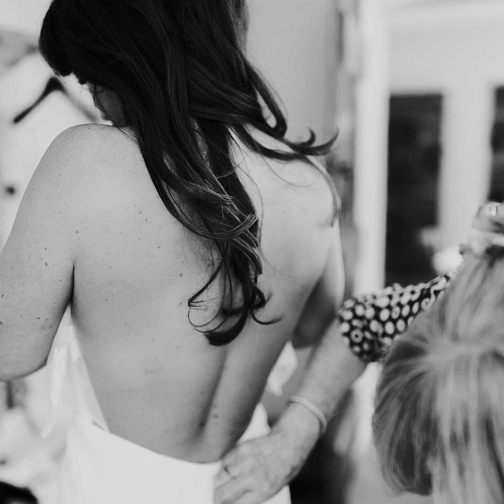 Black and white portrait on the wedding morning of the bride putting on her wedding dress