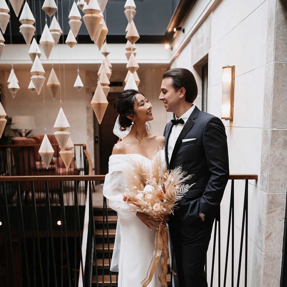 Groom in black suit with white shirt and bow tow and Bride in long fitted elegant dress 