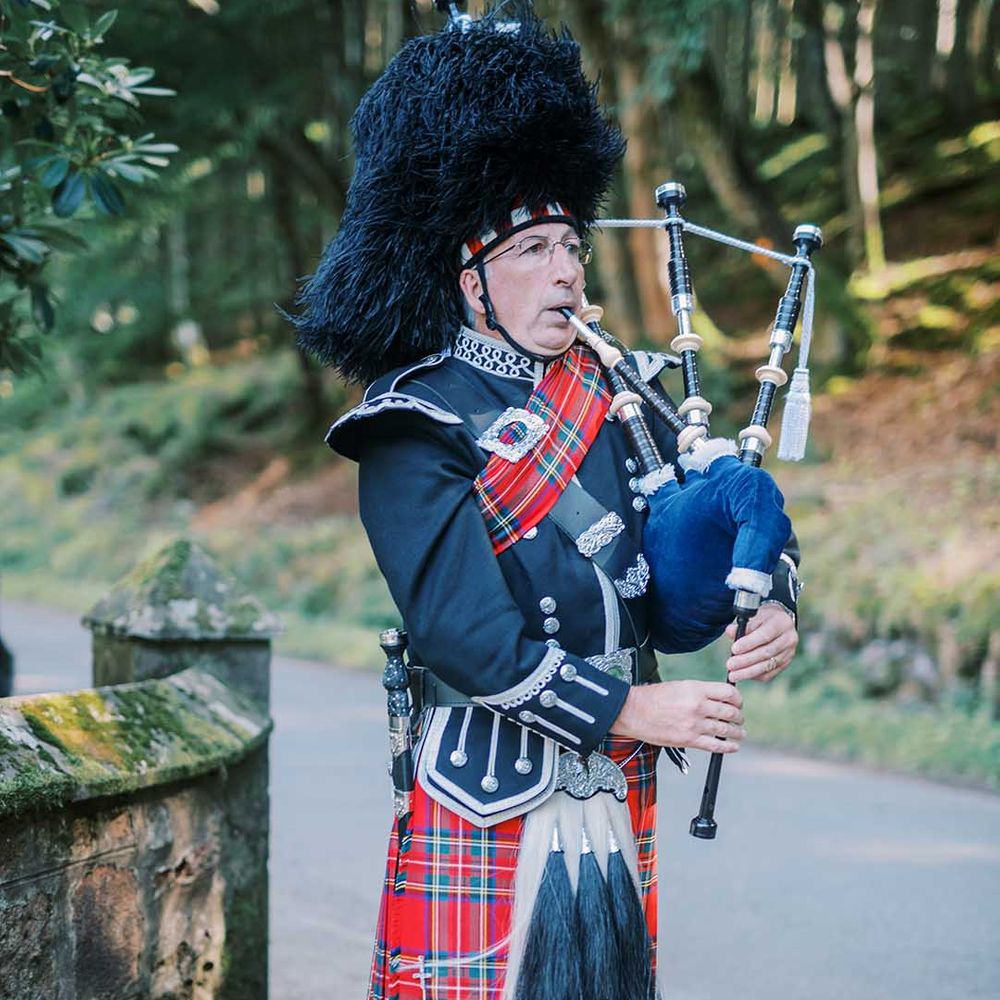 Scottish wedding with bag piper in a red tartan kilt 