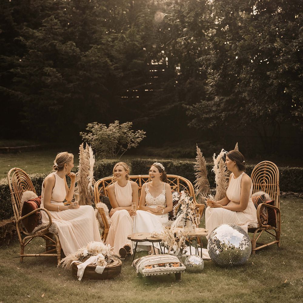 Bridesmaids sit outdoors next to disco balls with a 70s vibe