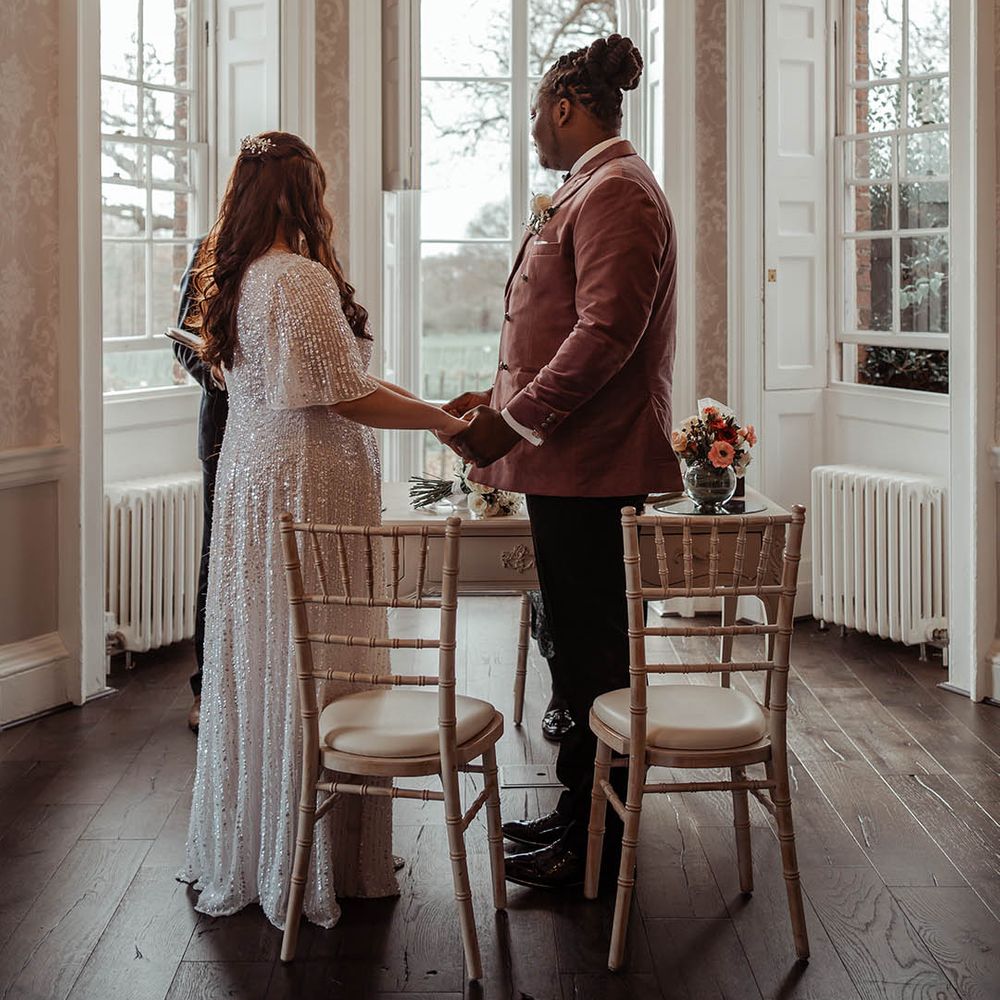 Bride & groom look lovingly at one another whilst holding hands during ceremony 