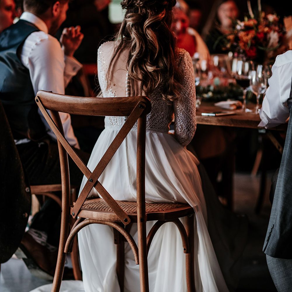 Bride with curled brown hair in half up half down hairstyle with dried flower and illusion lace back wedding dress with button detail 