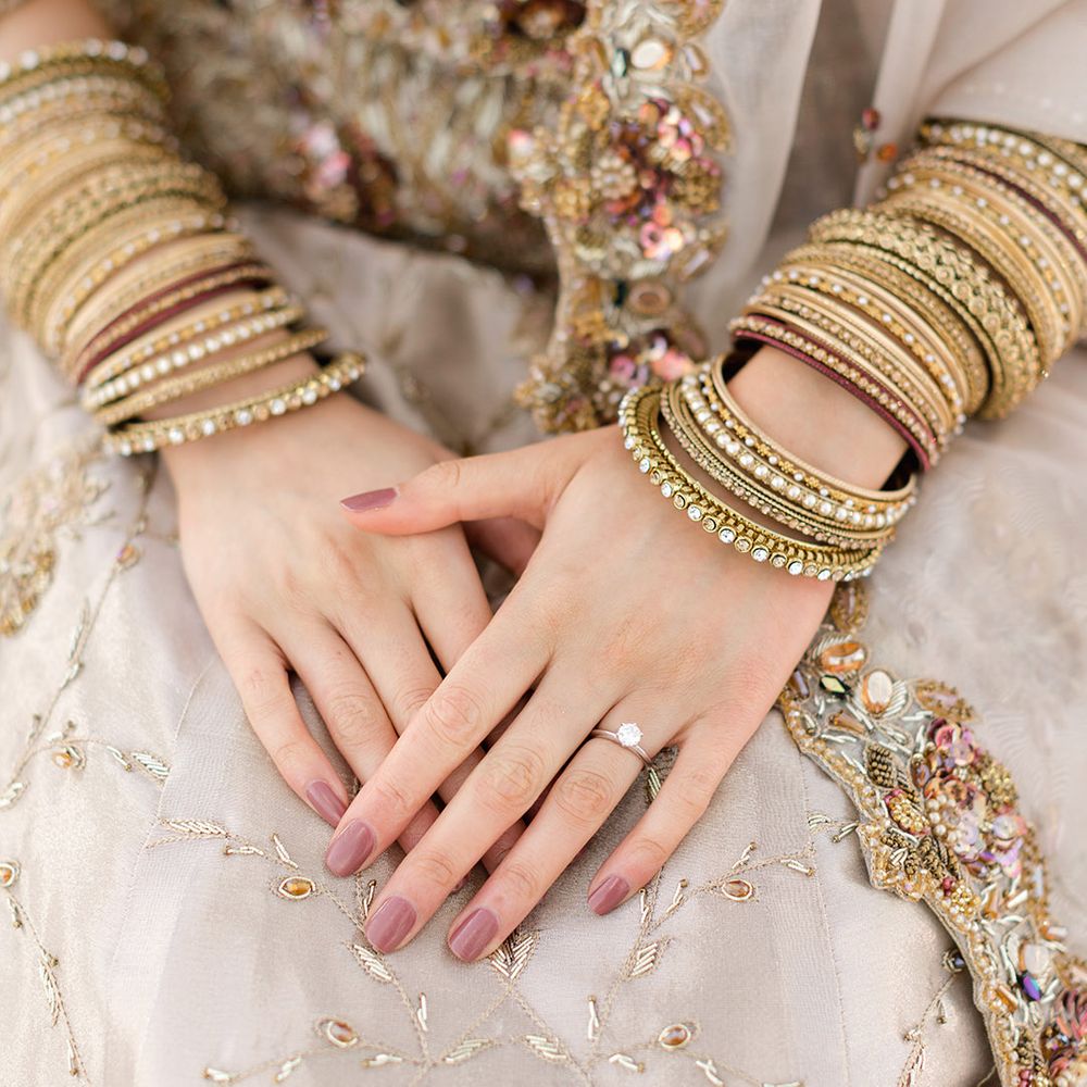 Bride wears gold bangles and purple nail varnish complete with diamond wedding ring 