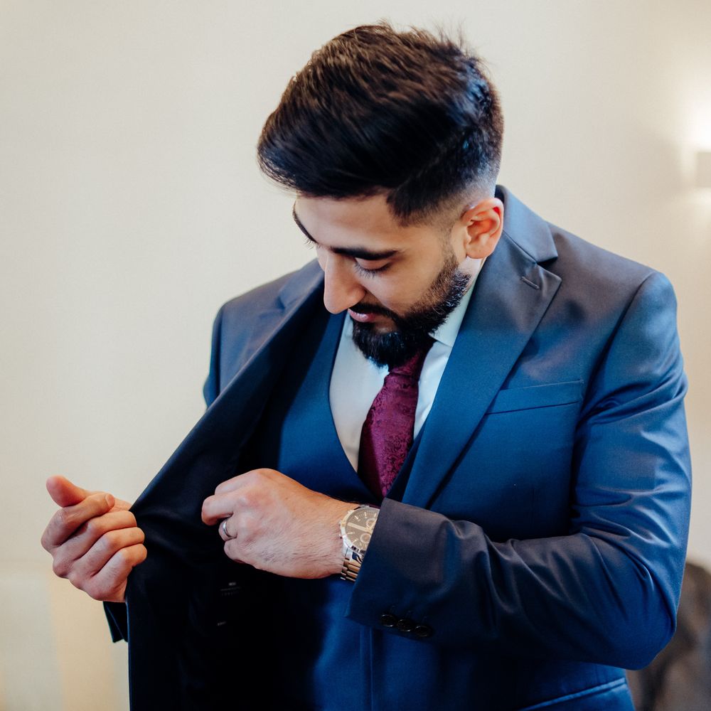 Groom wears deep blue three piece suit complete with purple tie for multicultural wedding 