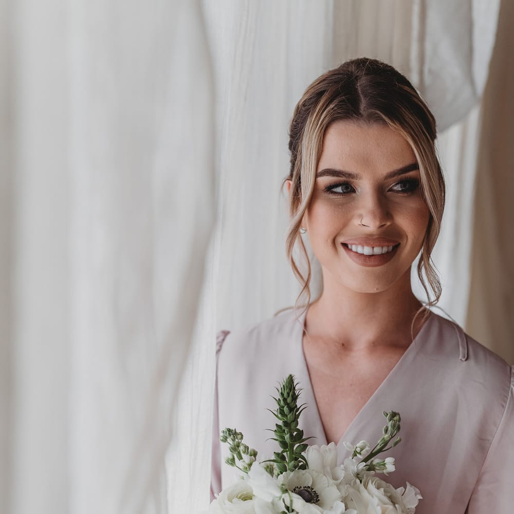 Bridesmaids in a pale bridesmaid dress holding a white flower bouquet 