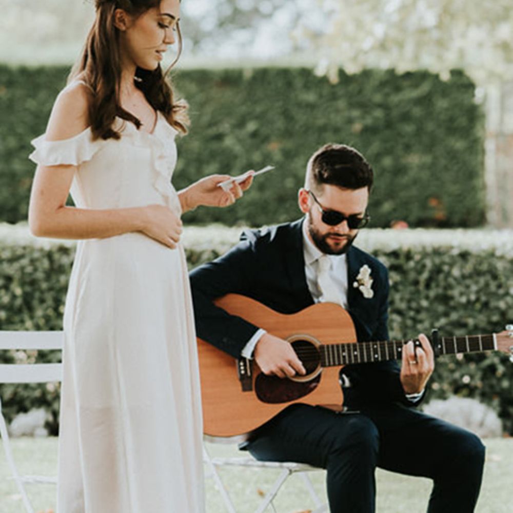 Wedding guest performs a wedding reading to a man playing the guitar 