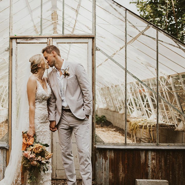 The bride and groom share a kiss in front of the greenhouse at Nancarrow Farm wedding venue 