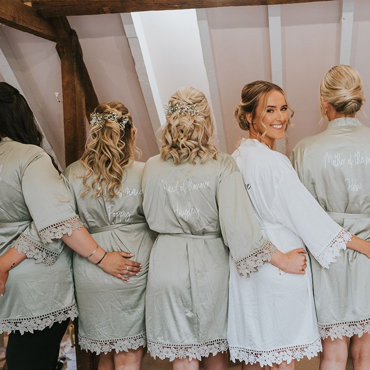 Bridesmaids in personalised sage green robes with the bride in a white robe 