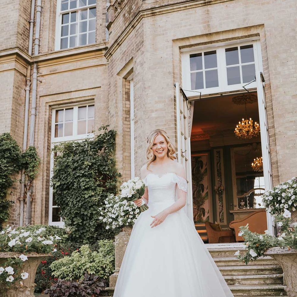 Bride in off shoulder lace detail wedding dress outside Hedsor House