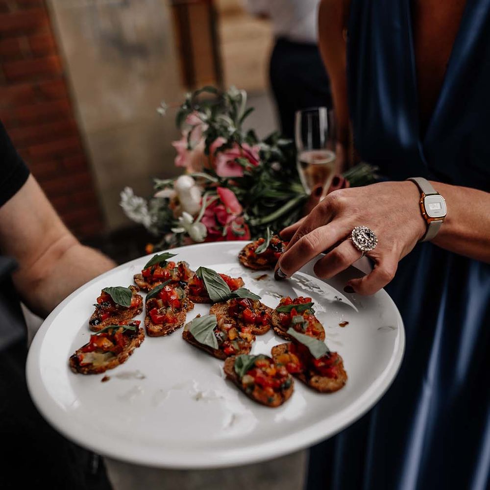 Guests taking small bruschetta canapés from sharing board at stylish wedding