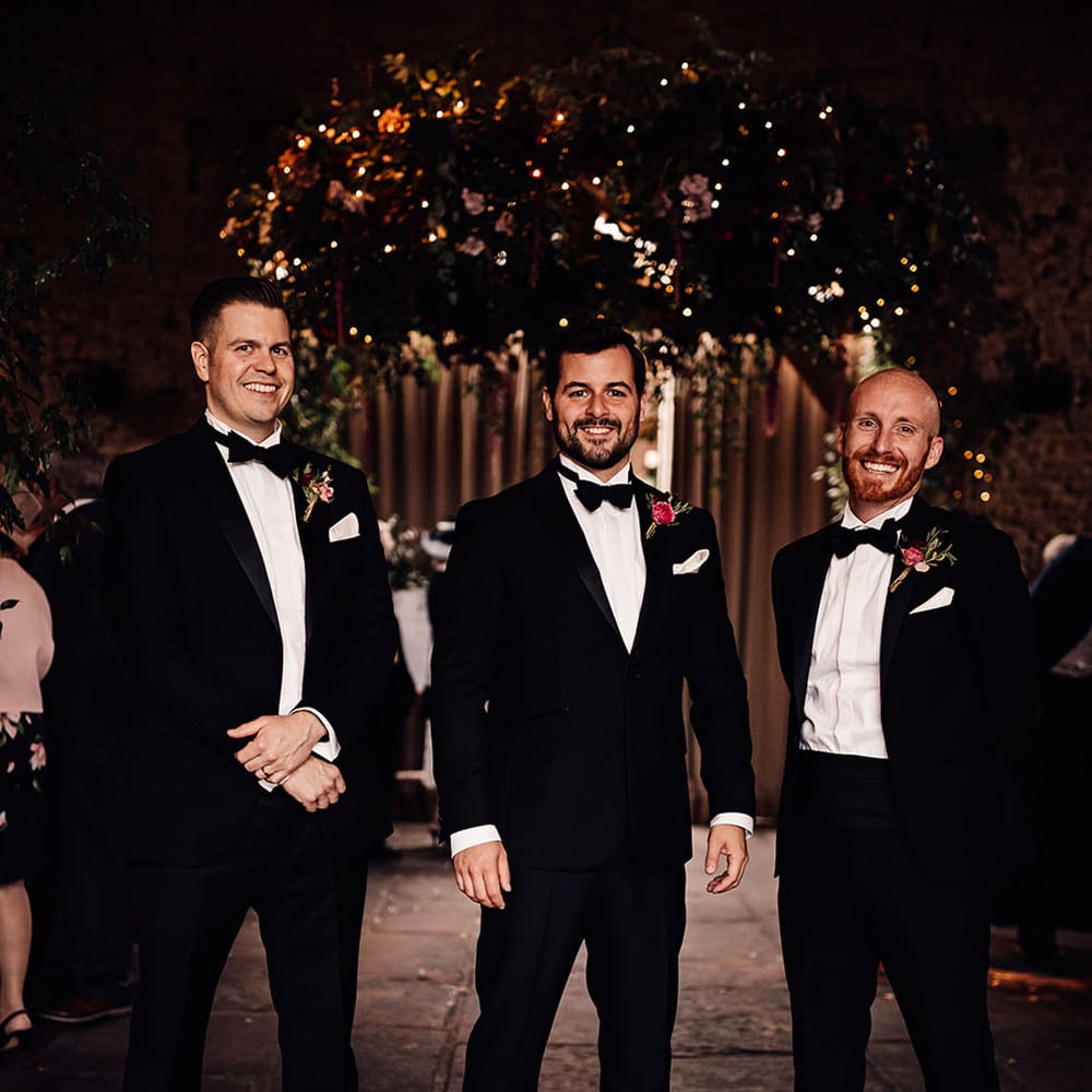 The groom stands with his groomsmen in matching black tuxedos for the wedding 