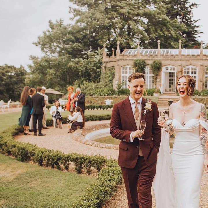 Bride & groom hold champagne outdoors at St Audries Park wedding venue